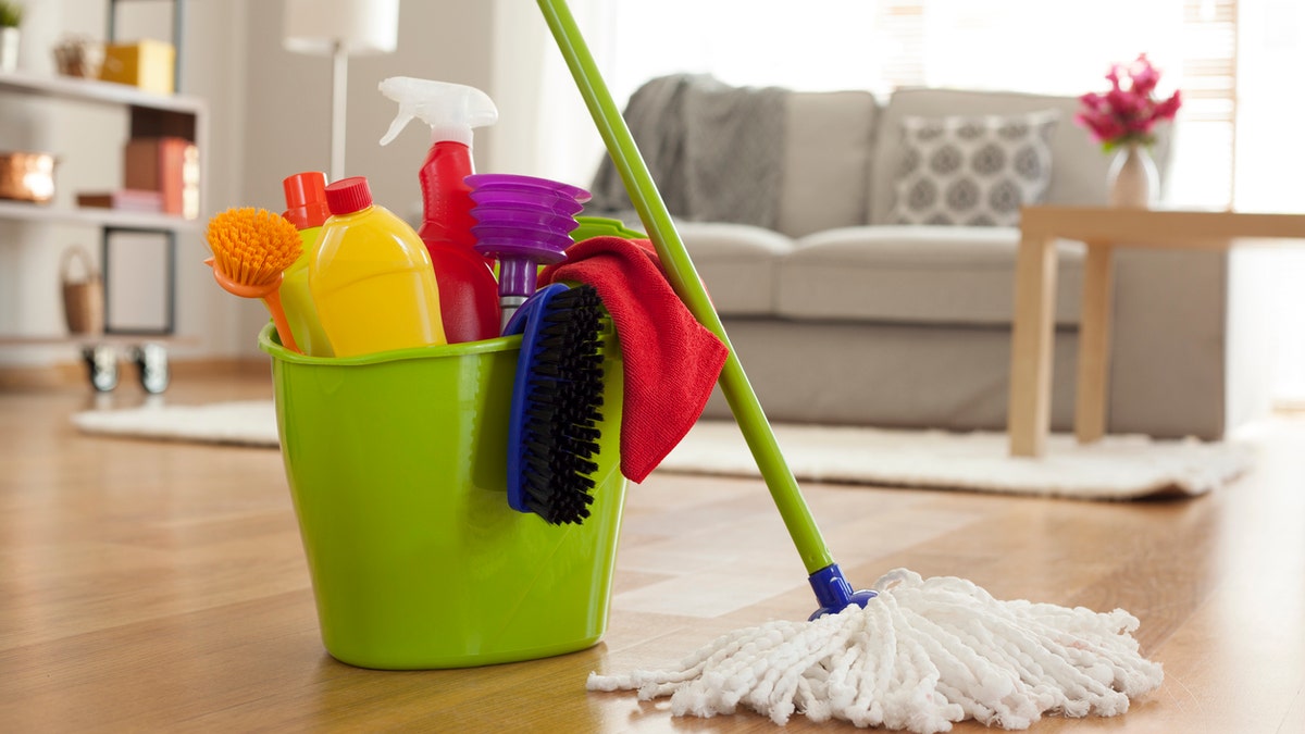 Plastic bucket with cleaning supplies in home