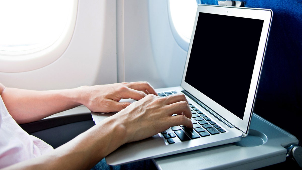 Man using laptop computer on airplane.