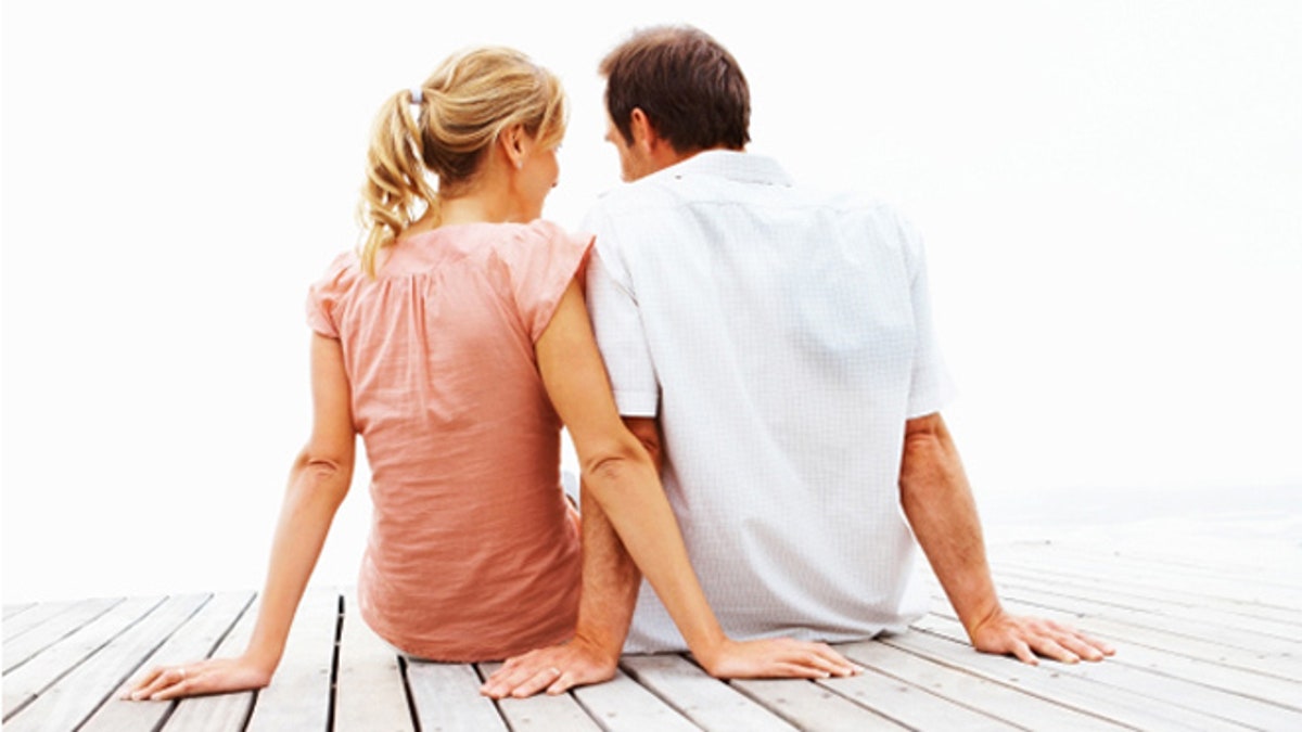 Couple sitting on a jetty over white background