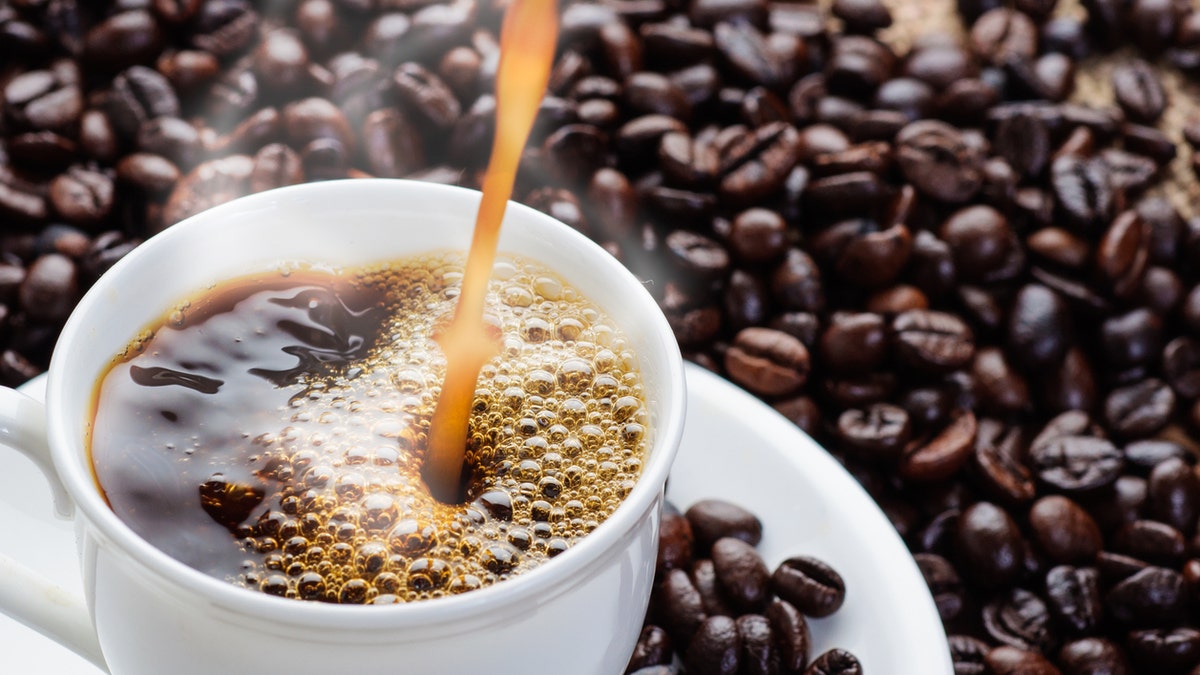 coffee pouring to cup surrounded by coffee beans