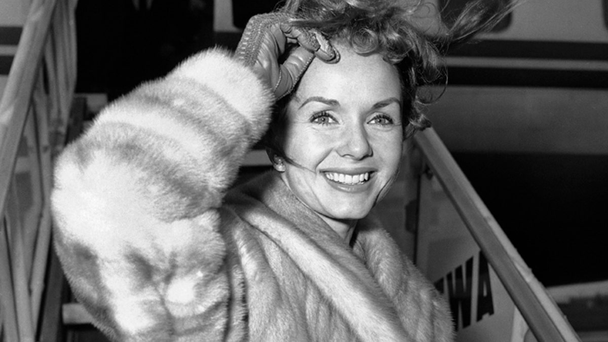 Screen actress Debbie Reynolds is a pretty wind-blown portrait as she boards airliner on March 6, 1959 in New York for Spain where she will film a new picture. She had flown in from California earlier in the day and contended with many questions about her divorced husband Eddie Fisher?s romance with Elizabeth Taylor. Said she: ?I wish them all happiness. That?s what we all want isn?t it?? (AP Photo/John Rooney)