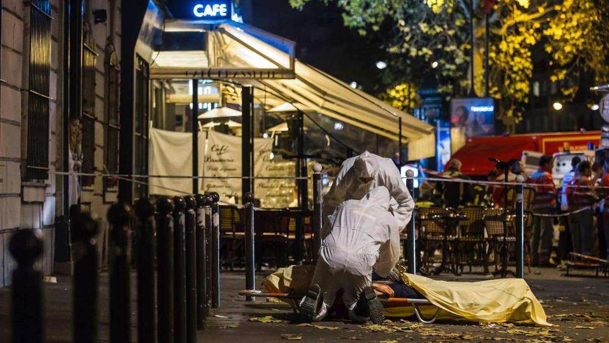 FILE - In this Friday, Nov. 13, 2015 file photo of Investigating police officers inspect the lifeless body of a victim of a shooting attack outside the Bataclan concert hall in Paris, France. With the scars and threat of extremist violence looming over France's presidential election, voters will cast ballots under a state of emergency that is becoming a part of the fabric of French life. (AP Photo/Kamil Zihnioglu, File)