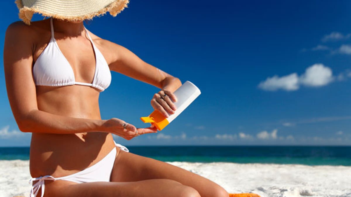 woman in the sun putting on sunscreen