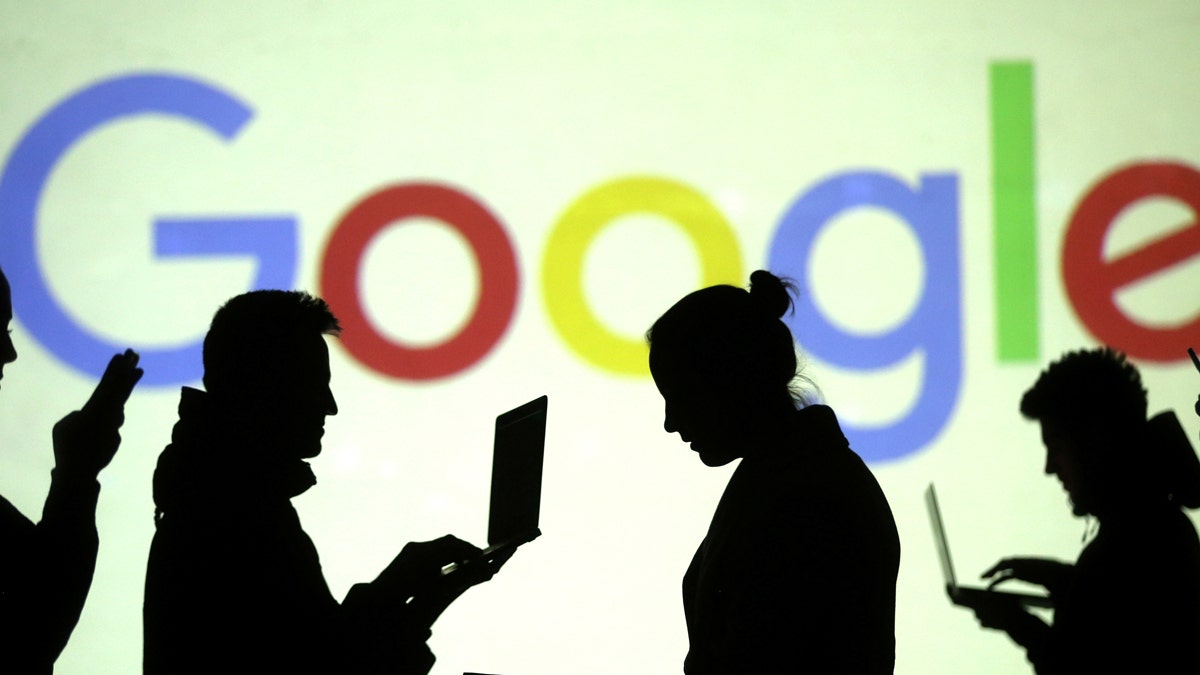 Silhouettes of laptop and mobile device users are seen next to a screen projection of Google logo in this picture illustration taken March 28, 2018.  REUTERS/Dado Ruvic/Illustration - RC1F87EA23D0