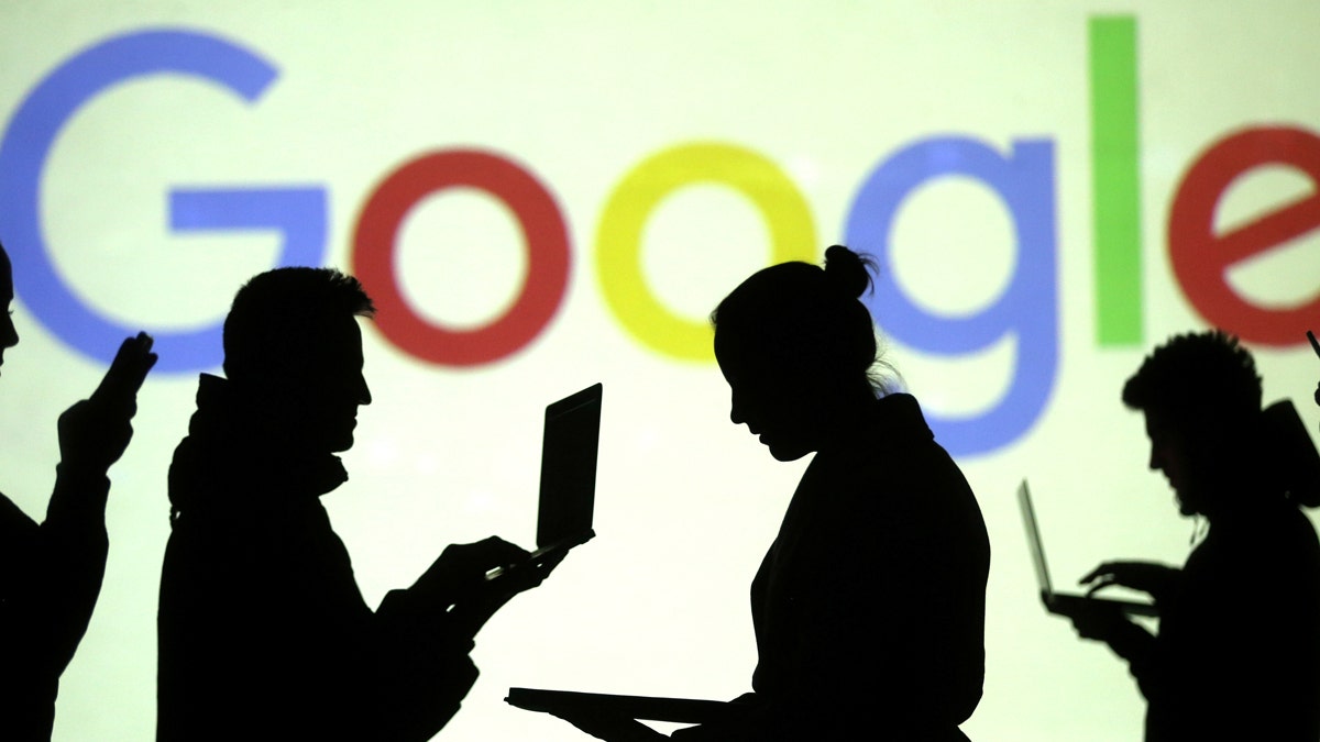 Silhouettes of laptop and mobile device users are seen next to a screen projection of Google logo in this picture illustration taken March 28, 2018.  REUTERS/Dado Ruvic/Illustration - RC1F87EA23D0