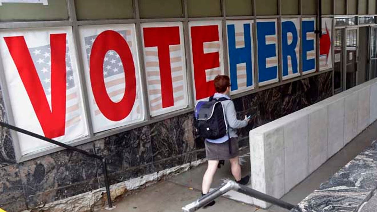 FILE - In this Sept. 23, 2016 file photo, a voter woman passes a large sign before voting in Minneapolis. If Donald Trump or Hillary Clinton scores a high note or commits a blunder in Sunday's presidential debate, millions of voters can respond almost immediately. They can fill out a mail-in ballot right away, or head to a polling location the next day. (AP Photo/Jim Mone, File)