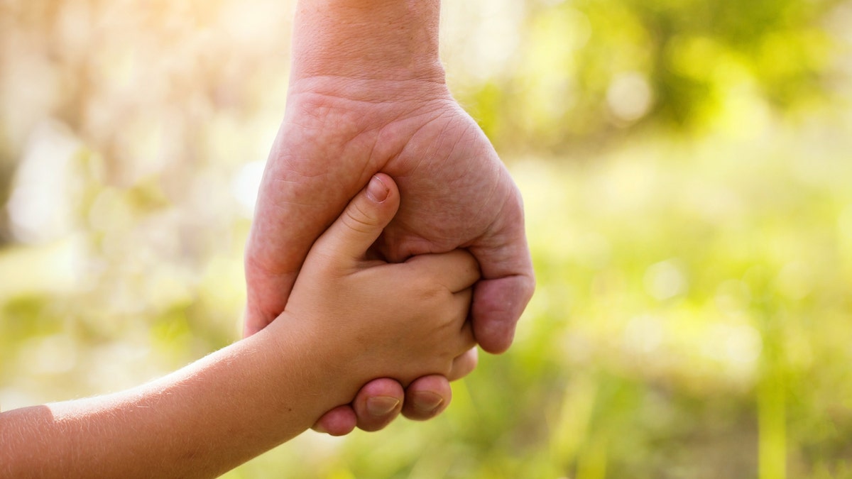 dad holding childs hand istock medium