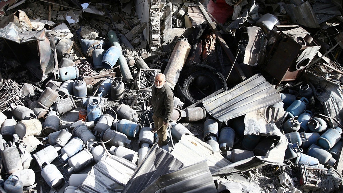 A man stands on the rubble of damaged buildings after an airstrike on the rebel-held town of Mesraba in the eastern Damascus suburb of Ghouta, Syria, November 26, 2017. REUTERS/Bassam Khabieh - RC149CB801E0