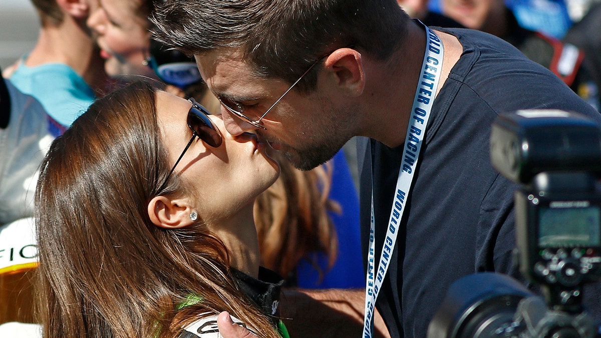 Danica Patrick, left, gets a kiss from Green Bay Packers quarterback Aaron Rodgers, right, before the NASCAR Daytona 500 Cup series auto race at Daytona International Speedway in Daytona Beach, Fla., Sunday, Feb. 18, 2018.