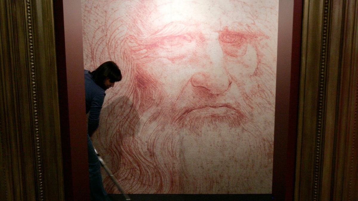 A cleaner vacuums in front of a Leonardo da Vinci self-portrait drawn around 1515 or 1516, during the inauguration of the exhibition 
