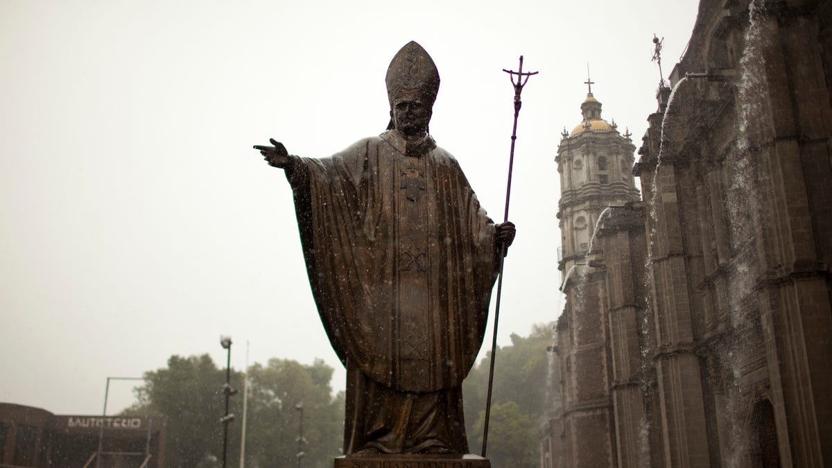 A statue of Pope John Paul II stands outside the Basilica of Guadalupe during heavy rain in Mexico City, Friday, July 5, 2013. Pope Francis on Friday approved the miracle of a Costa Rican woman bringing John Paul to the ranks of saints. Floribeth Mora suffering from a cerebral aneurysm and only given a month to live, was inexplicably cured on May 1, 2011, the date of John Paul's beatification, when millions of worshippers filled St. Peter's Square to honor the beloved Polish pontiff. (AP Photo/Ivan Pierre Aguirre)