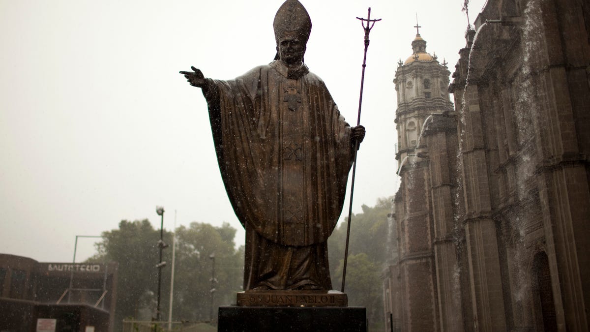 A statue of Pope John Paul II stands outside the Basilica of Guadalupe during heavy rain in Mexico City, Friday, July 5, 2013. Pope Francis on Friday approved the miracle of a Costa Rican woman bringing John Paul to the ranks of saints. Floribeth Mora suffering from a cerebral aneurysm and only given a month to live, was inexplicably cured on May 1, 2011, the date of John Paul's beatification, when millions of worshippers filled St. Peter's Square to honor the beloved Polish pontiff. (AP Photo/Ivan Pierre Aguirre)