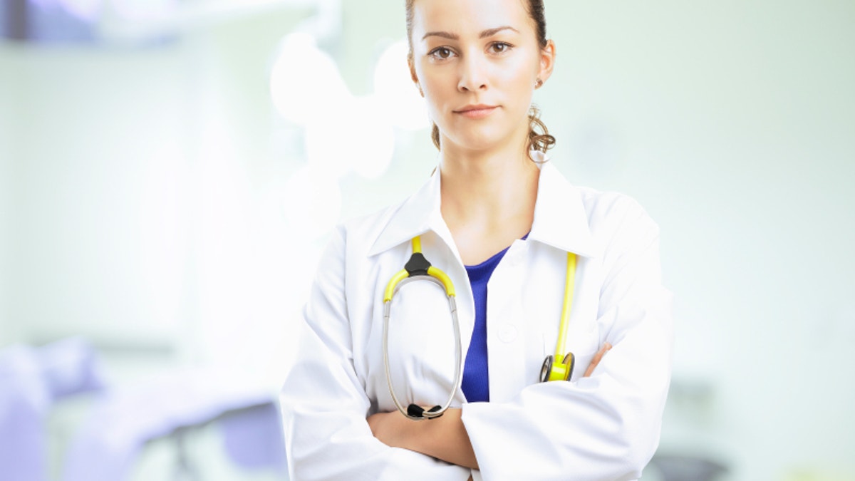 Young female doctor arms crossed standing at private clinic. 