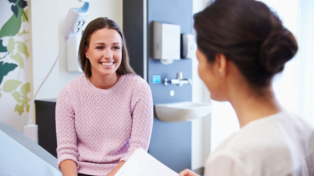 Female Patient And Doctor Have Consultation In Hospital Room