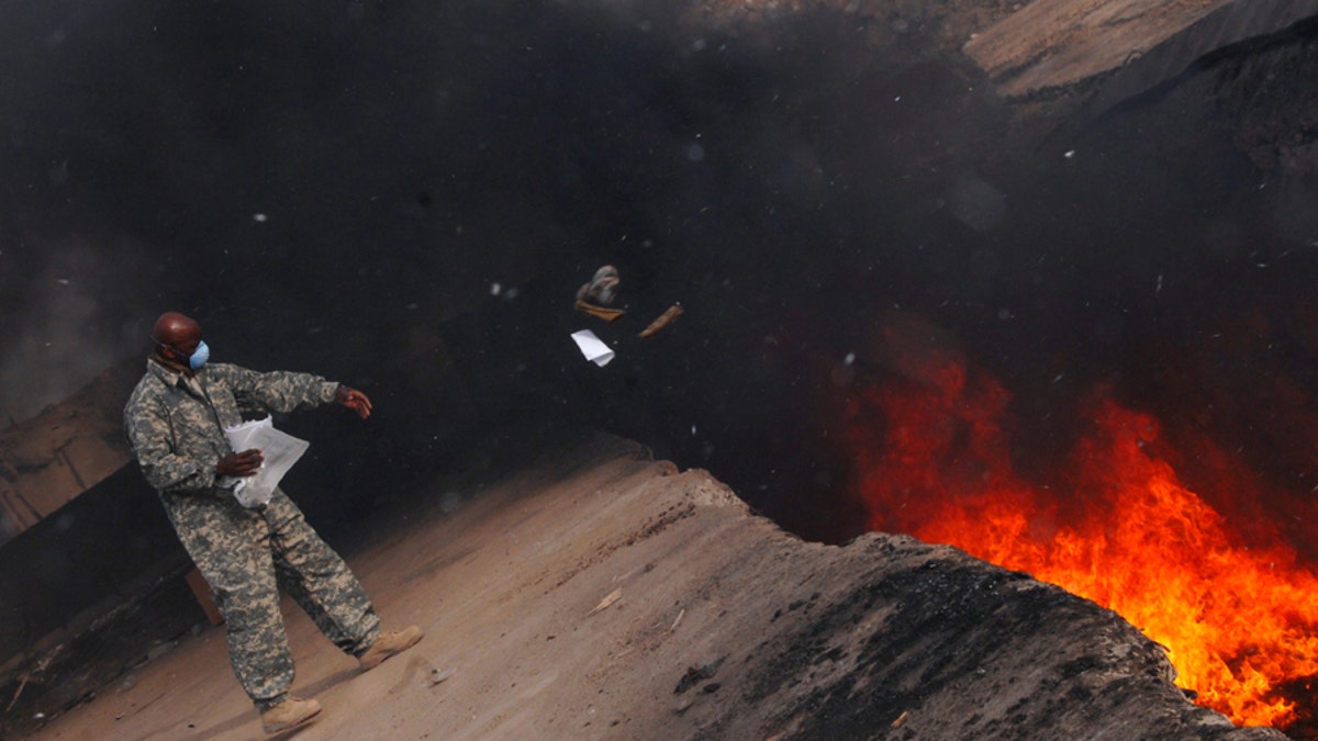 Master Sgt. Darryl Sterling, 332nd Expeditionary Logistics Readiness Squadron equipment manager, tosses unserviceable uniform items into a burn pit here, March 10. The 332 ELRS has a central collection point that can be used by service members and Department of Defense civilians; unserviceable uniform items are burned. Sergeant Sterling is deployed from Luke Air Force Base, Ariz.