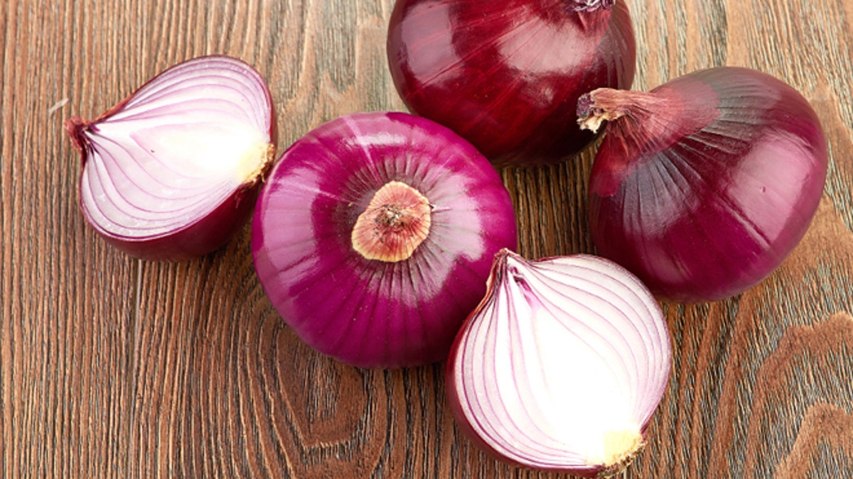 Fresh red onions on a wooden background