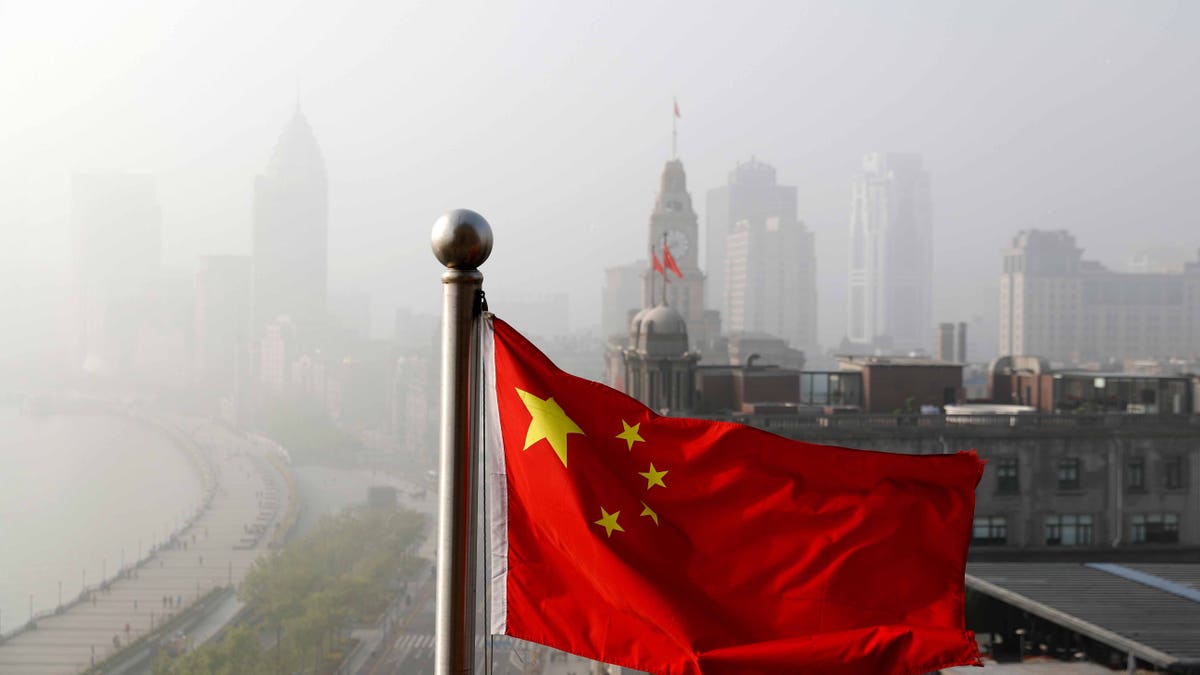 A Chinese national flag flutters against the office buildings at the Shanghai Bund shrouded by pollution and fog in Shanghai, China, Thursday, April 14, 2016. World finance officials who meet in Washington this week confront a bleak picture: Eight years after the financial crisis erupted, the global economy remains fragile and at risk of another recession. (AP Photo/Andy Wong)