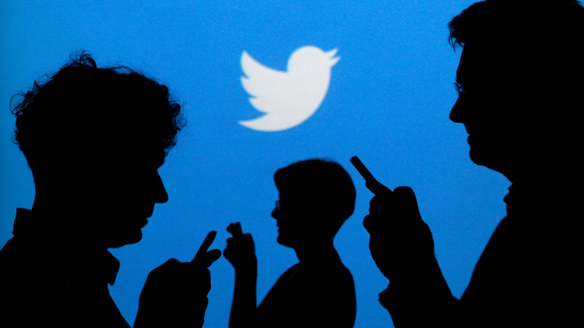 People holding mobile phones are silhouetted against a backdrop projected with the Twitter logo in this illustration picture taken in Warsaw September 27, 2013. Twitter Inc, the eight-year-old online messaging service, gave potential investors their first glance at its financials on Thursday when it publicly filed its IPO documents, setting the stage for one of the most-anticipated debuts in over a year. Picture taken September 27. REUTERS/Kacper Pempel (POLAND - Tags: BUSINESS TELECOMS LOGO) - BM2E9A410KY01