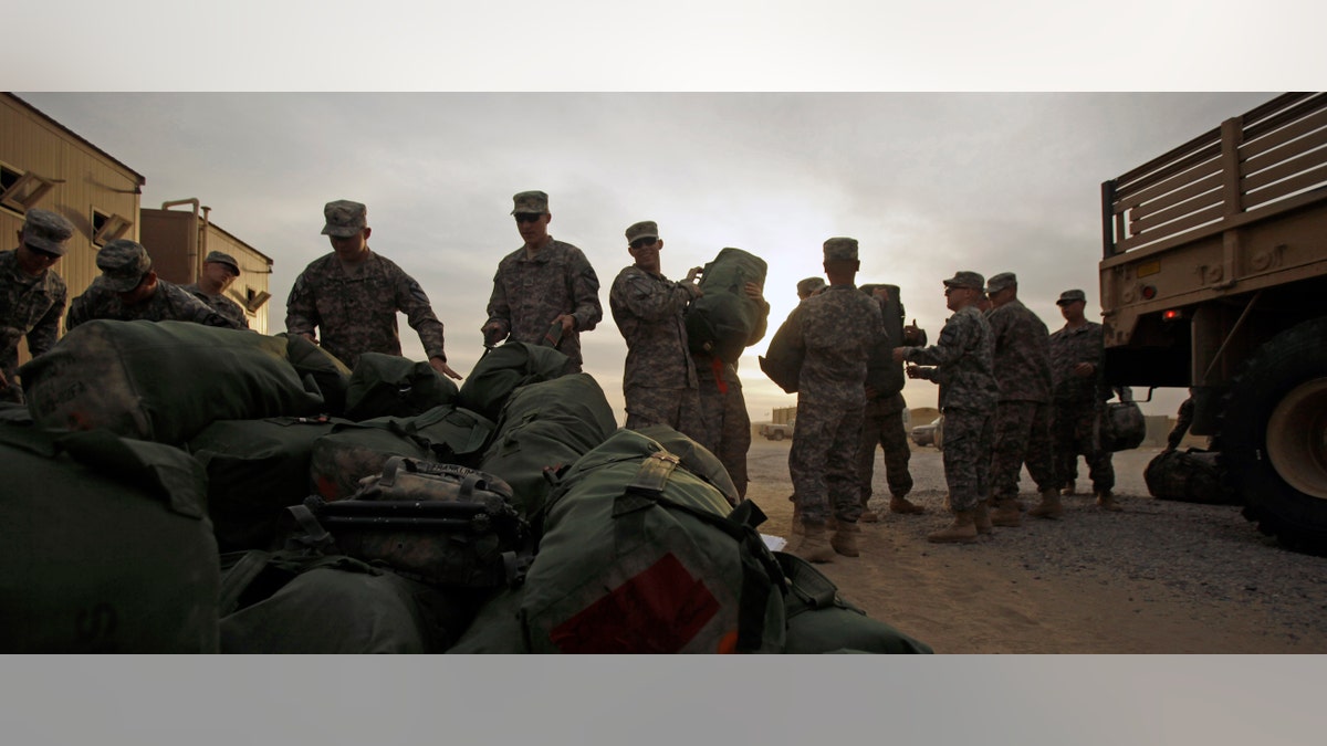 U.S. Army soldiers from 1st Cavalry Division, based at Fort Hood, Texas, load their baggage as they begin their journey home after a deployment in Iraq, at Camp Virginia, Kuwait, Thursday, Dec. 15, 2011. After nearly nine years, 4,500 American dead and 100,000 Iraqi dead, U.S. officials formally shut down the war in Iraq - a conflict that Defense Secretary Leon Panetta said was worth the American sacrifice because it set Iraq on a path to democracy. (AP Photo/Maya Alleruzzo)