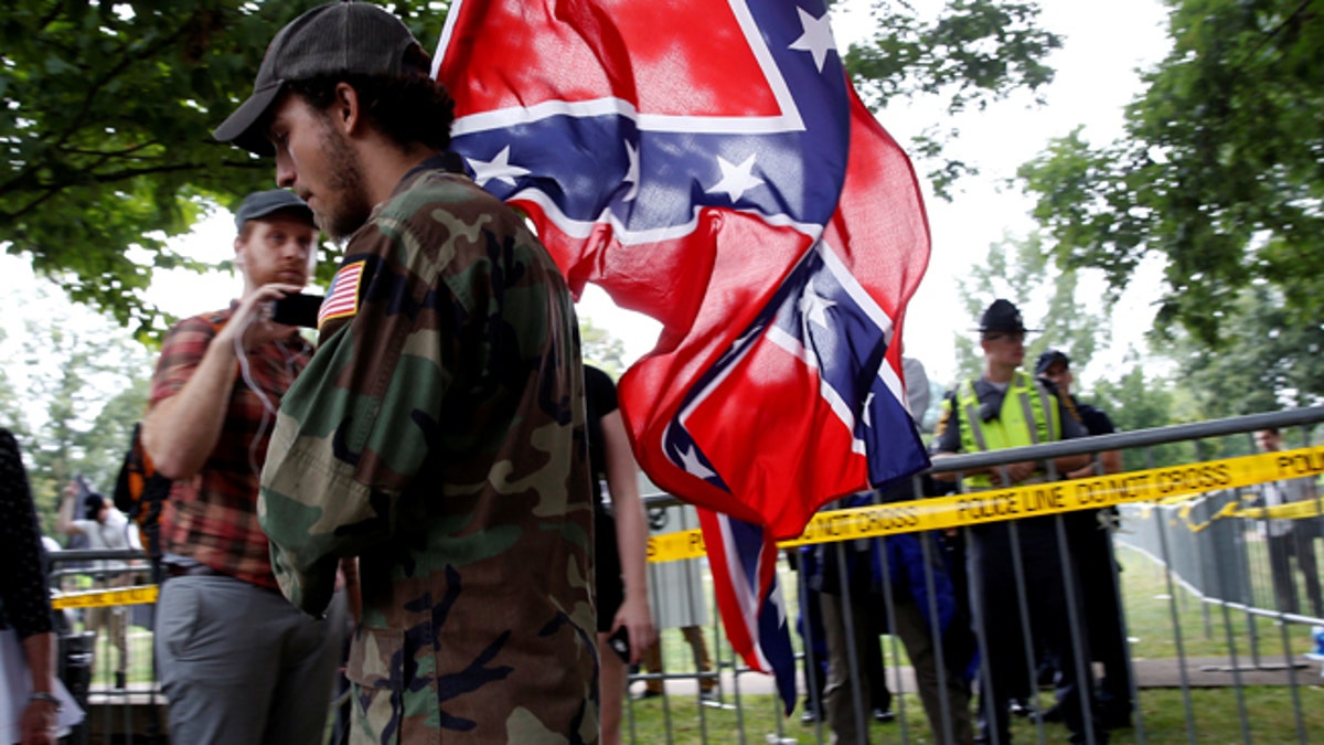 A white nationalist carries the Confederate flag as he arrives for a rally in Charlottesville, Virginia, U.S., August 12, 2017. REUTERS/Joshua Roberts - RTS1BI7C