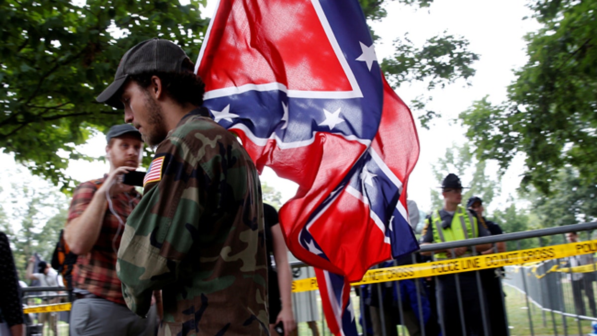 A white nationalist carries the Confederate flag as he arrives for a rally in Charlottesville, Virginia, U.S., August 12, 2017. REUTERS/Joshua Roberts - RTS1BI7C