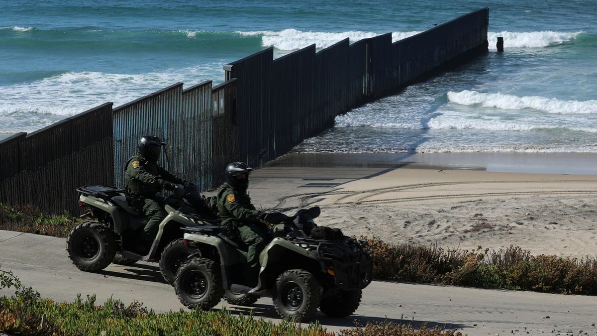U.S. Customs and Border patrol agents on all-terrain vehicles look over over the Mexico- U.S. border wall where it enters the Pacific Ocean at Border Field State Park in San Diego, California, U.S., November 18, 2017. REUTERS/Mike Blake - RC1A9C0A7F90