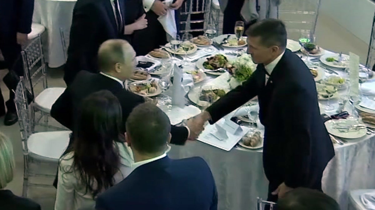 In this image made from a video taken on Dec. 10, 2015 and made available on Tuesday, Feb. 14, 2017, US President Donald Trump's former National Security Advisor Michael Flynn, right, shakes hands with Russian President Vladimir Putin, in Moscow. Flynn, who resigned following reports that he misled White House officials about his contacts with Russia, was seen attending the 10th anniversary of the Russian television network RT in 2015 where Russian President Vladimir Putin gave a speech. A US official has told The Associated Press that Flynn was in frequent contact with Ambassador Sergey Kislyak on the day the Obama administration imposed sanctions on Russia after US intelligence reported that Russia had interfered with the US elections. (Ruptly via AP)