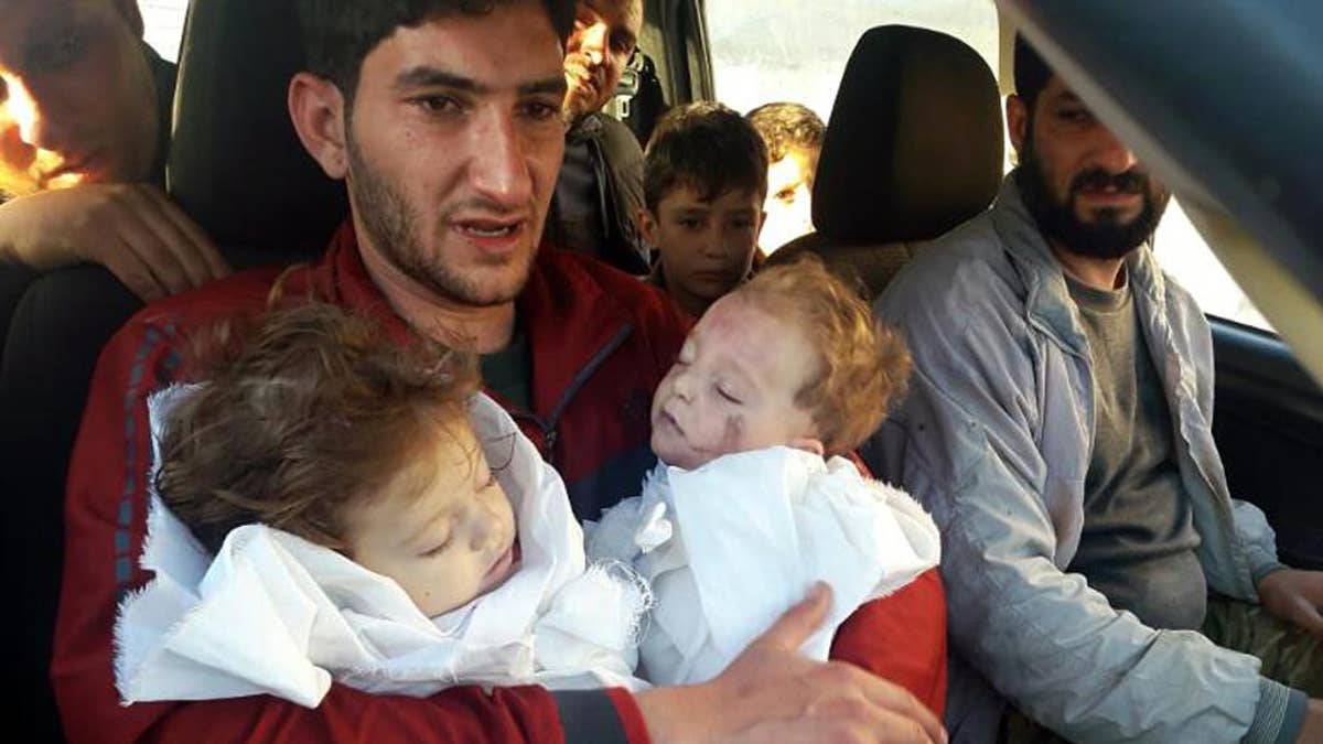FILE -- In this Tuesday April 4, 2017 file photo, Abdel Hameed Alyousef, 29, holds his twin babies who were killed during a suspected chemical weapons attack, in Khan Sheikhoun in the northern province of Idlib, Syria. France's foreign minister says chemical analysis of samples taken from a deadly sarin gas attack in Syria shows that the nerve agent used 