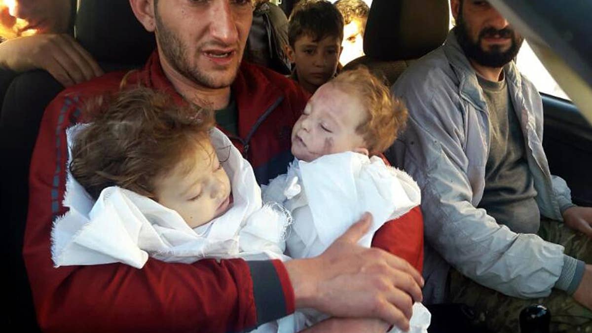 FILE -- In this Tuesday April 4, 2017 file photo, Abdel Hameed Alyousef, 29, holds his twin babies who were killed during a suspected chemical weapons attack, in Khan Sheikhoun in the northern province of Idlib, Syria. France's foreign minister says chemical analysis of samples taken from a deadly sarin gas attack in Syria shows that the nerve agent used 