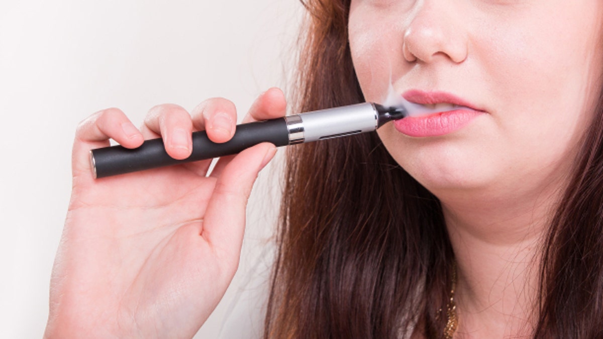 Woman smoking e-cigarette on a white background