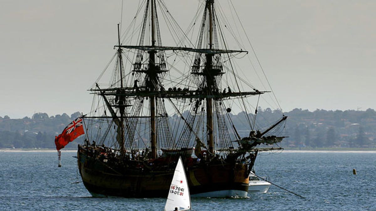 Crew members sit atop the masts of a replica of the famous 18th century ship The Endeavour in Botany Bay.  