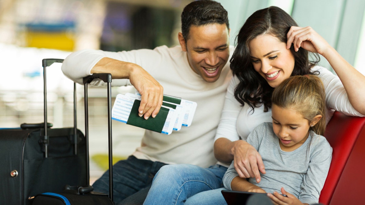 little girl using tablet pc with parents at airport