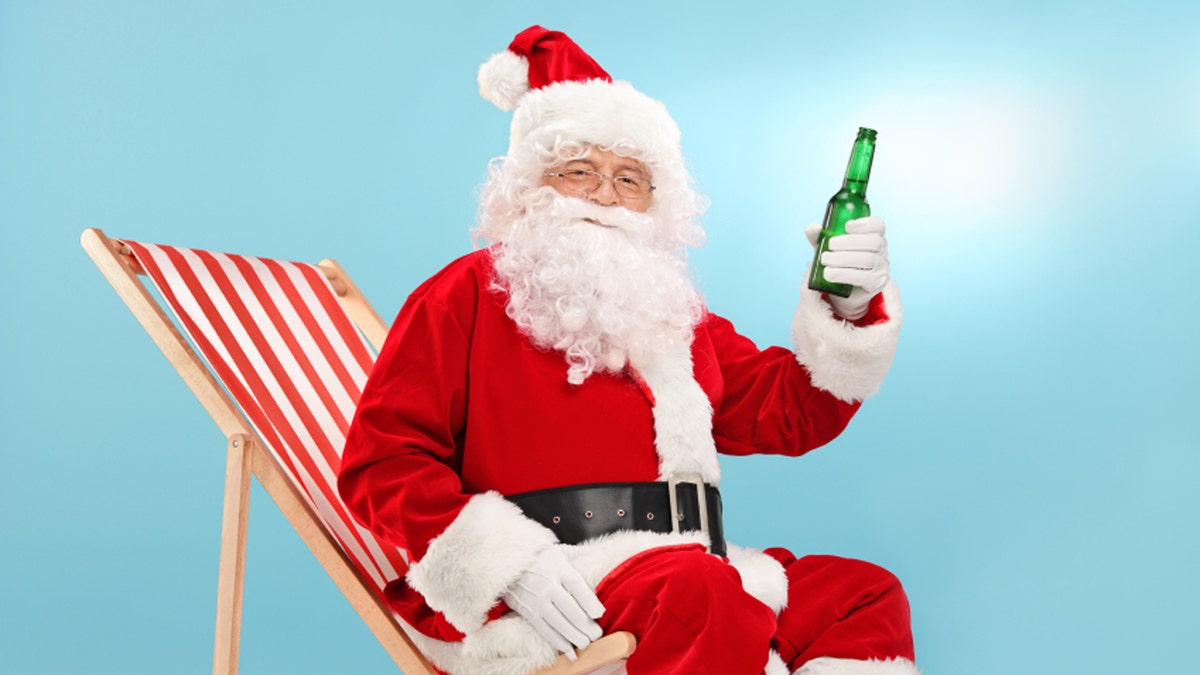 Santa Claus holding beer seated on a sun lounger