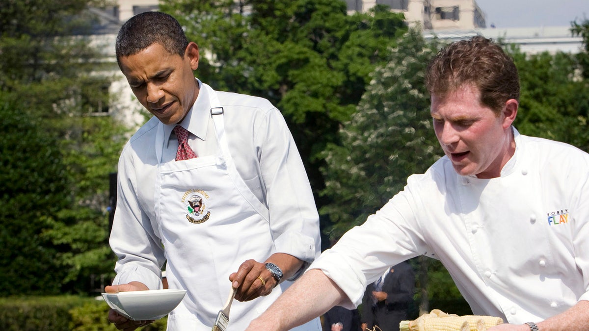 U.S. President Barack Obama stands next to celebrity chef Bobby Flay (R) at the grill as he hosts a barbeque for local school students on the South Lawn of the White House in Washington June 19, 2009. REUTERS/Larry Downing (UNITED STATES POLITICS) - RTR24U4R