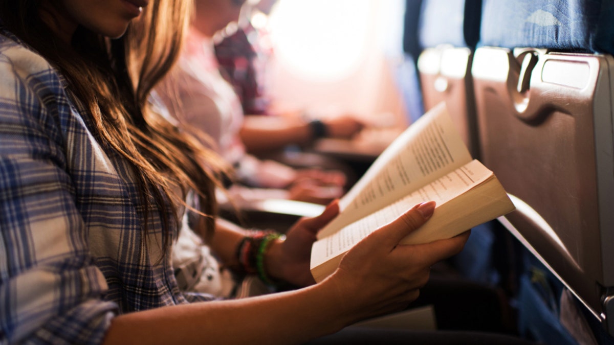 Reading a book while travelling by airplane.