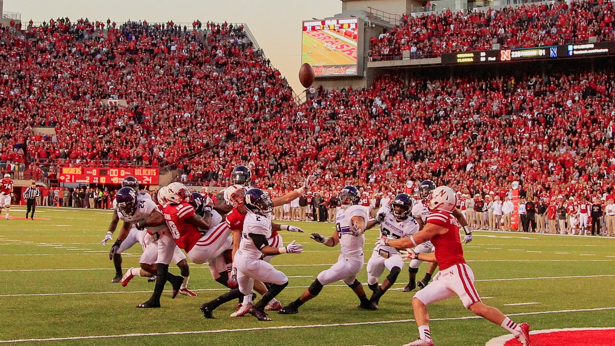 In this image from Nov. 2, 2013, a scrum of Nebraska and Northwestern players follow a tipped ball after Nebraska wide receiver Quincy Enunwa (18), Northwestern center back Dwight White (2), safety Traveon Henry (10), and safety Ibraheim Campbell (24), vied for a ball thrown by Nebraska quarterback Ron Kellogg III (12) with no time on the clock, in an NCAA college football game in Lincoln, Neb.The ball was subsequently caught by Nebraska wide receiver Jordan Westerkamp, right, for a touchdown, giving Nebraska a 27-24 win. If Nebraska makes it back to the Big Ten championship game, the Cornhuskers might look at Westerkamp's tipped-ball touchdown on the last play against Northwestern as the one that saved their season and maybe even Bo Pelini's job. (AP Photo/Nati Harnik)