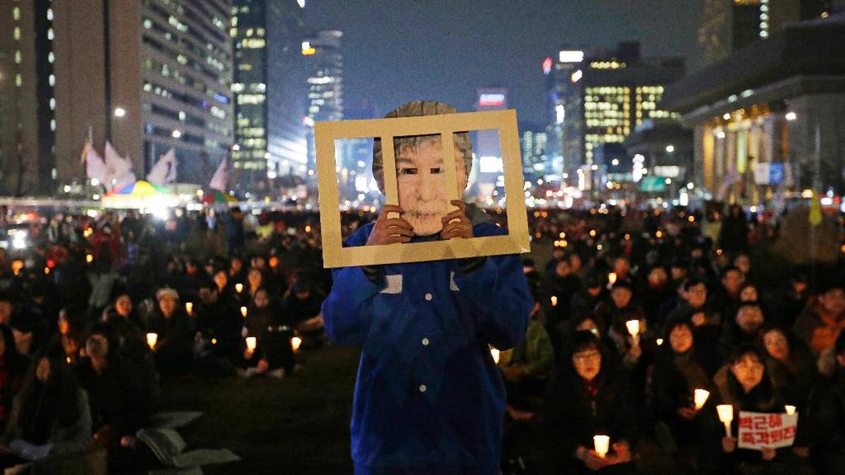 A protester wearing a mask of the president performs Wednesday during a rally calling for Park to step down in Seoul.