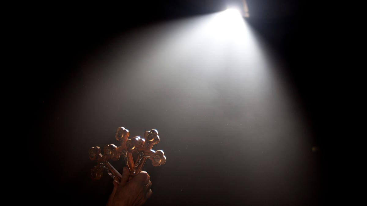 A Christian Orthodox pilgrim raises her hand while holding three crosses towards a beam of light in front of the Edicule at the Church of the Holy Sepulchre, traditionally believed to be the site of the crucifixion of Jesus Christ, during the ceremony of the Holy Fire in Jerusalem's Old City Saturday, May 4, 2013. (AP Photo/Ariel Schalit)