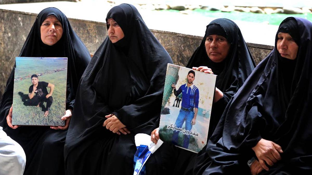 Mothers hold up posters of their sons,  Iraqi soldiers who were killed, at a courtroom in Baghdad, Iraq, Wednesday, July 8, 2015. An Iraqi court has issued death sentences to 24 militants for their role in killing hundreds of soldiers last year. The slain soldiers were captured by the Islamic State group when they overran Saddam Hussein's hometown of Tikrit in summer 2014. At the time, the soldiers were trying to flee from a nearby army base. (AP Photo/ Karim Kadim