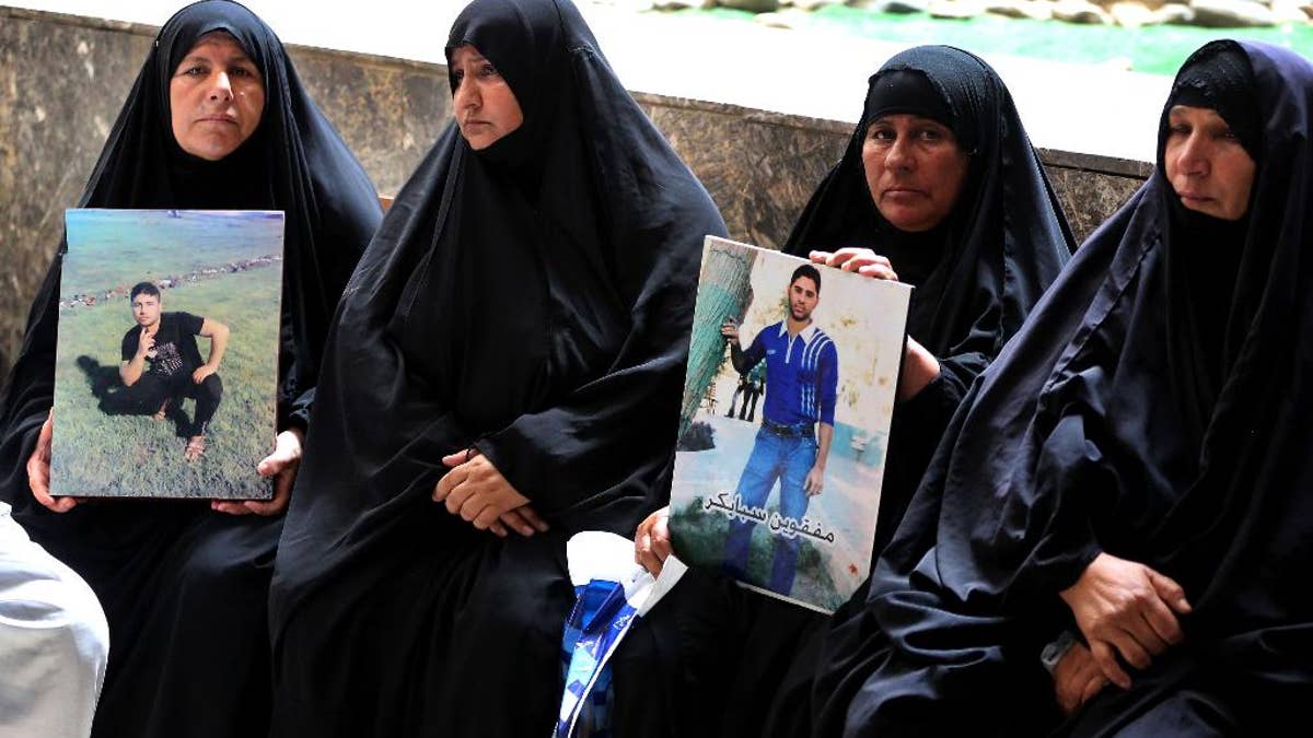 Mothers hold up posters of their sons, Iraqi soldiers who were killed, at a courtroom in Baghdad, Iraq, Wednesday, July 8, 2015. An Iraqi court has issued death sentences to 24 militants for their role in killing hundreds of soldiers last year. The slain soldiers were captured by the Islamic State group when they overran Saddam Hussein's hometown of Tikrit in summer 2014. At the time, the soldiers were trying to flee from a nearby army base. (AP Photo/ Karim Kadim