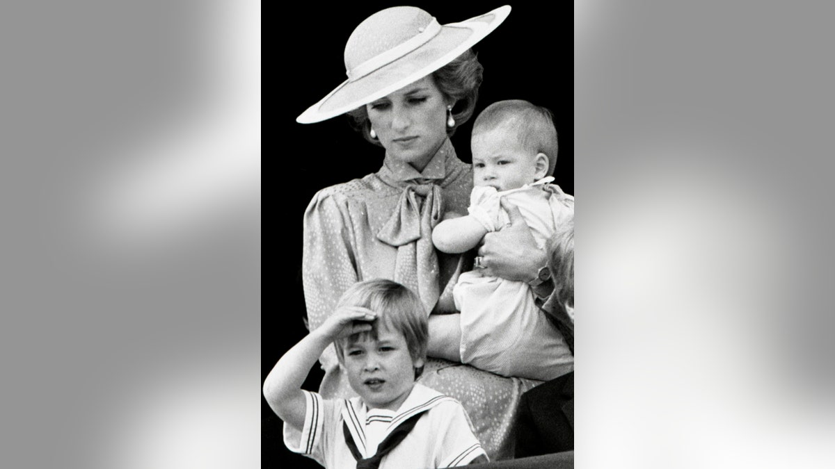 Prince William makes a royal salute as he watches the scene of Trooping the Colour from the balcony of Buckingham Palace with his brother Harry and mother Princess Diana on June 15, 1985 in London.  REUTERS/Roy Letkey - RTR1JWRG