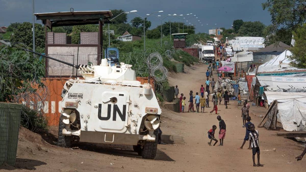 In this photo taken Monday, July 25, 2016, some of the more than 30,000 Nuer civilians sheltering in a United Nations base in South Sudan's capital Juba for fear of targeted killings by government forces walk by an armored vehicle and a watchtower manned by Chinese peacekeepers. South Sudanese government soldiers raped dozens of ethnic Nuer women and girls last week just outside a United Nations camp where they had sought protection from renewed fighting, and at least two died from their injuries, witnesses and civilian leaders said. The rapes in the capital of Juba highlighted two persistent problems in the chaotic country engulfed by civil war: targeted ethnic violence and the reluctance by U.N. peacekeepers to protect civilians. (AP Photo/Jason Patinkin)