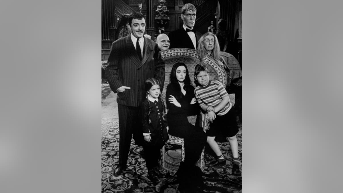 Carolyn Jones (C, sitting) and John Astin (L), with other cast members, during scene from program