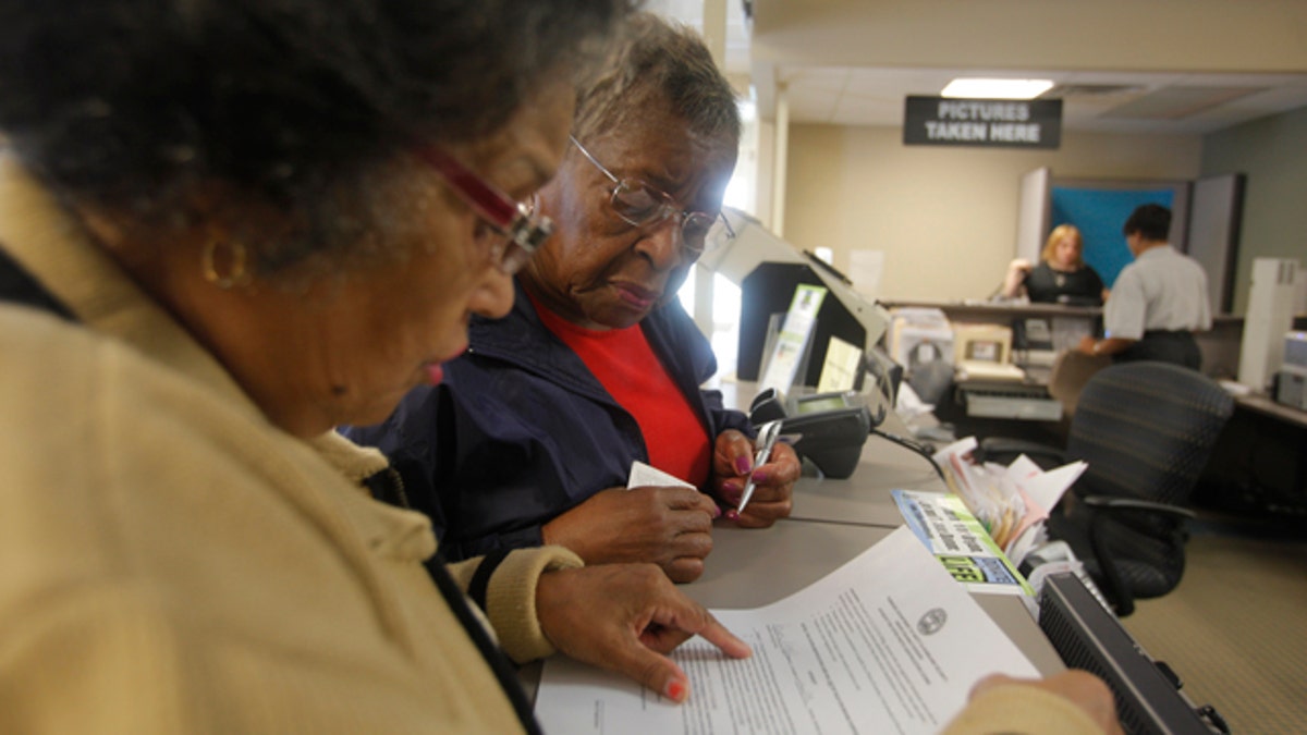 In this photo taken Sept. 19, 2011, Dorothy Melvin, center, gets help from Charline Kilpatrick as she fills out a form to get a new license with her photograph on it. Dorothy and Joshua Melvin added photos to their drivers licenses at the Driver Services Center on Monday afternoon. Several states adopted new laws last year requiring people to show a photo ID when they come to the polls to vote, even though the voter fraud that the laws are designed to stamp out rarely happens. (AP Photo/Chattanooga Times Free Press, Jake Daniels)