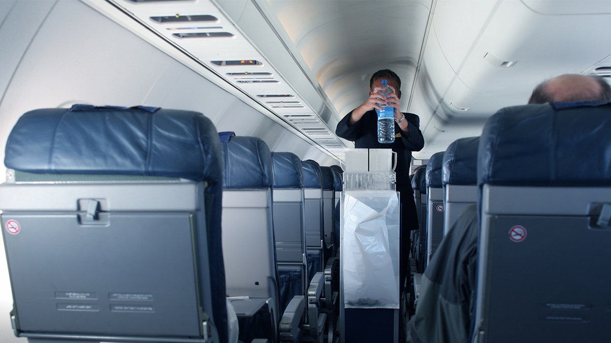 Flight attendant collecting trash.