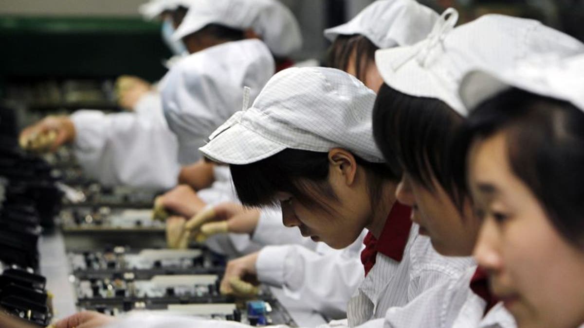 FILE-In this Wednesday, May 26, 2010, file photo, staff members work on the production line at the Foxconn complex in Shenzhen, China. Foxconn, the company that makes Apples iPhones suspended production at a factory in China on Monday, Sept. 24, 2012, after a brawl by as many as 2,000 employees at a dormitory injured 40 people.  The fight, the cause of which was under investigation, erupted Sunday night at a privately managed dormitory near a Foxconn Technology Group factory in the northern city of Taiyuan, the company and Chinese police said.(AP Photo/Kin Cheung, File)