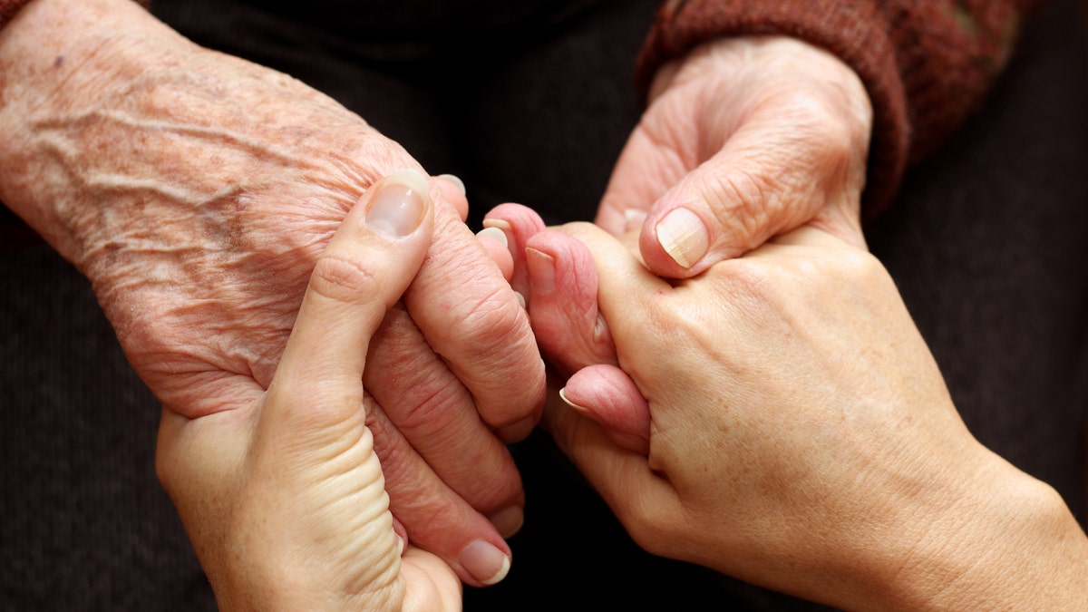 The hands of a young woman takes those of an older person as a sign of support and help