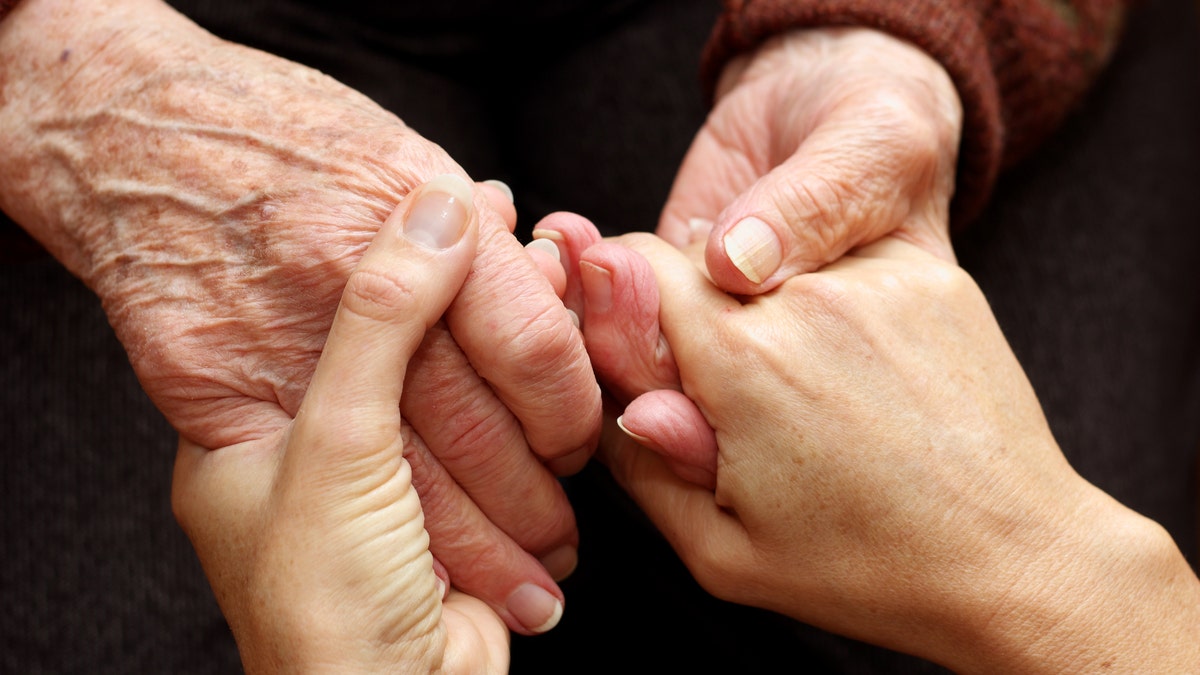 The hands of a young woman takes those of an older person as a sign of support and help