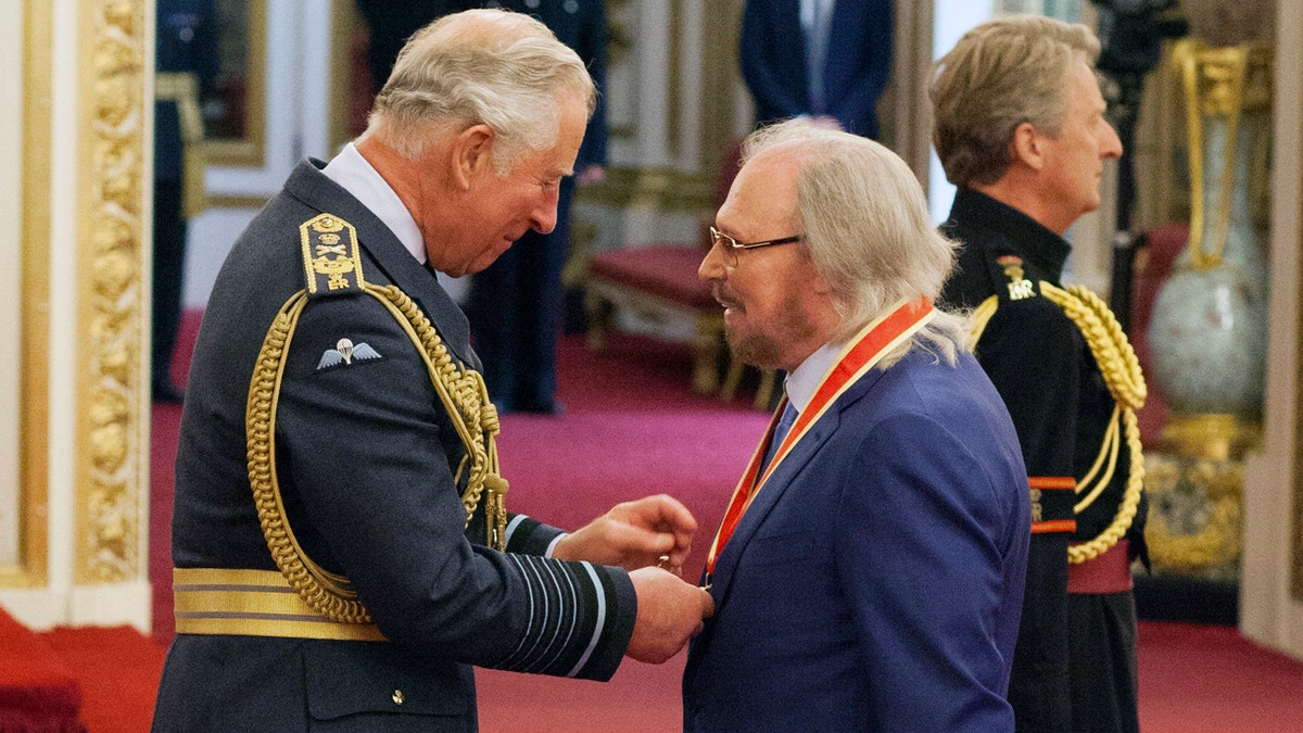 Singer and songwriter Barry Gibb talks with Prince Charles, left, during an Investiture ceremony to award a knighthood to Gibb, at Buckingham Palace in London, Tuesday June 26, 2018. (Dominic Lipinski/PA via AP)
