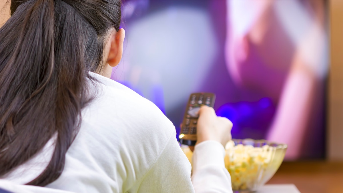girl watching tv while eating junk food istock large